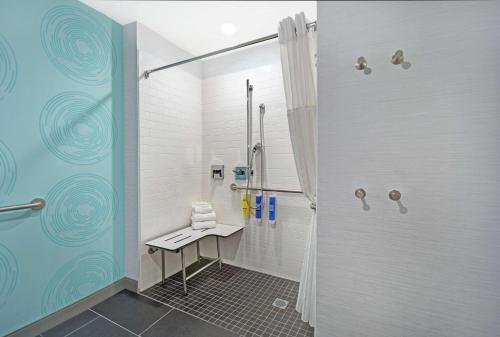 a bathroom with a shower with a bench in it at Tru By Hilton Grand Rapids Airport in Kentwood