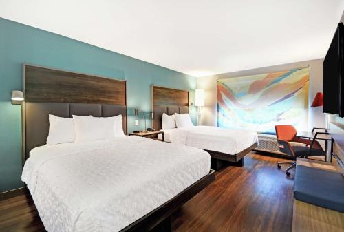 um quarto de hotel com duas camas e uma cadeira em Tru By Hilton Grand Rapids Airport em Kentwood