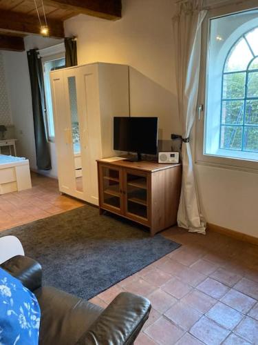 a living room with a tv on a wooden cabinet at Idylle unter Reet, gemütliche Ferienwohnug in Haseldorf