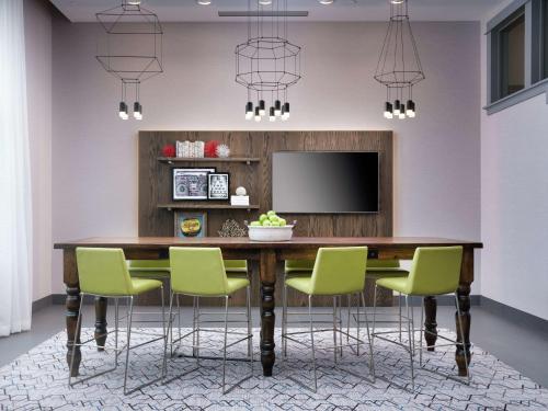 a dining room table with green chairs and a television at Hampton Inn & Suites Atlanta Decatur/Emory in Decatur