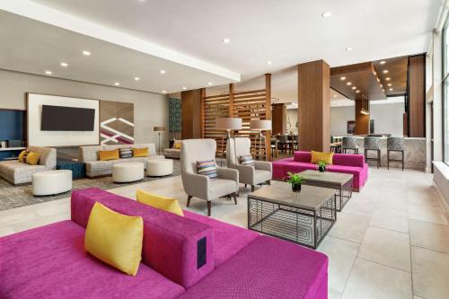 a living room with a purple couch and chairs at Hilton Garden Inn Seattle Airport in SeaTac