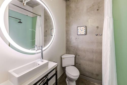 a bathroom with a sink and a toilet and a mirror at NYLO Las Colinas Hotel, Tapestry Collection by Hilton in Irving