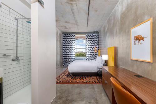 Habitación con baño con cama y ducha. en NYLO Las Colinas Hotel, Tapestry Collection by Hilton en Irving
