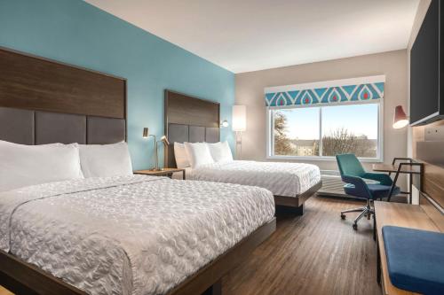 a hotel room with two beds and a chair and a window at Tru By Hilton Greenville Woodruff Road, SC in Greenville