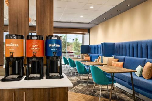 a waiting room with tables and blue chairs at Tru Lawrenceville Atlanta I85 Sugarloaf in Lawrenceville