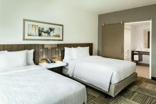 a hotel room with two beds and a bathroom at Hilton Garden Inn Wenatchee, Wa in Wenatchee