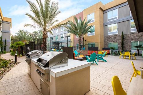 a outdoor patio with a grill and tables and chairs at Home2 Suites By Hilton Carlsbad, Ca in Carlsbad