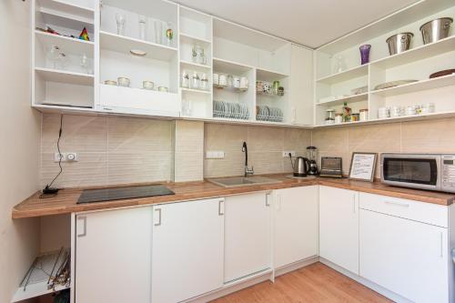 a kitchen with white cabinets and a microwave at Palanga 777 - poilsio namai prie Birutės parko ir jūros in Palanga
