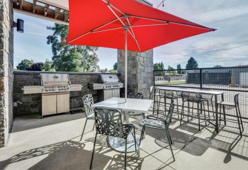 a table and chairs with a red umbrella on a patio at Home2 Suites By Hilton Yakima Airport in Yakima