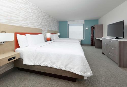 a bedroom with a large bed and a flat screen tv at Home2 Suites By Hilton Yakima Airport in Yakima