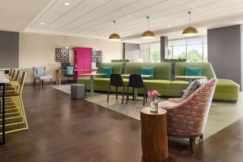a lobby with a green couch and tables and chairs at Home2 Suites By Hilton Overland Park, Ks in Overland Park