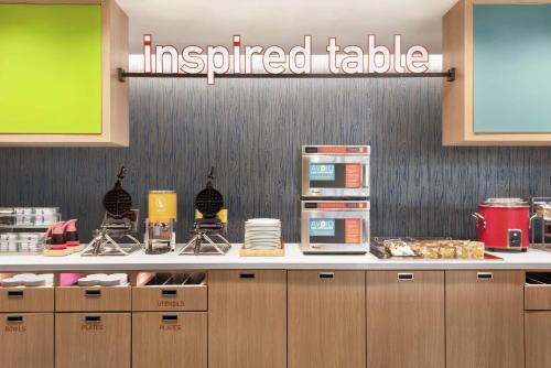 alined table in a restaurant with a sign on the wall at Home2 Suites By Hilton Overland Park, Ks in Overland Park