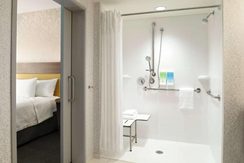 a bathroom with a shower and a bed at Home2 Suites By Hilton Overland Park, Ks in Overland Park