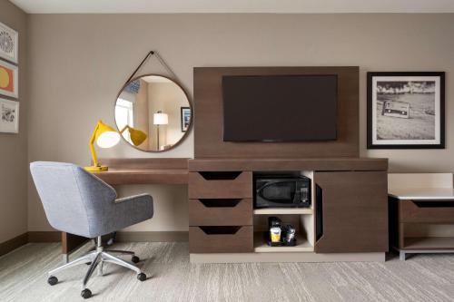 a room with a desk with a television and a mirror at Hampton Inn & Suites Ocean City West in Ocean City
