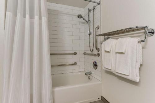 ein Bad mit einer Badewanne und einer Dusche mit Handtüchern in der Unterkunft DoubleTree by Hilton St. Louis Forest Park in Saint Louis