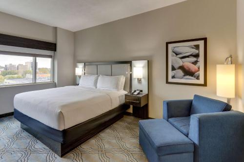 ein Hotelzimmer mit einem Bett und einem Stuhl in der Unterkunft DoubleTree by Hilton St. Louis Forest Park in Saint Louis