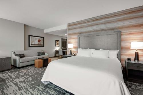um quarto de hotel com uma cama grande e um sofá em Embassy Suites Jonesboro - Arkansas State em Jonesboro