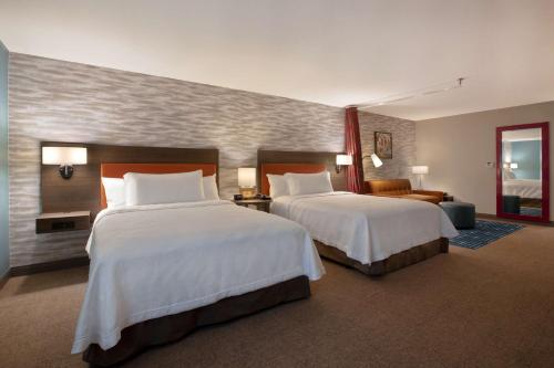 a hotel room with two beds and a couch at Home2 Suites By Hilton Loves Park Rockford in Loves Park