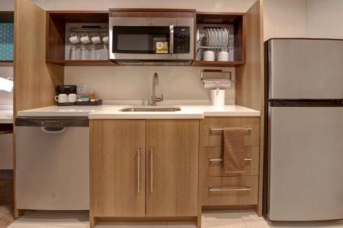 a kitchen with a sink and a refrigerator at Home2 Suites By Hilton Loves Park Rockford in Loves Park