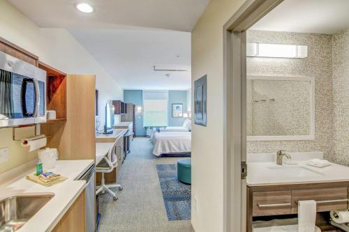 un bagno con lavandino e un letto in una camera di Home2 Suites By Hilton Foley a Foley