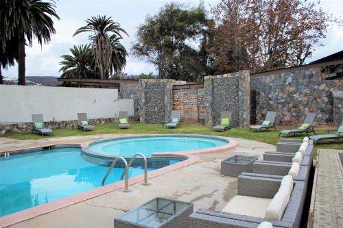 a swimming pool in a yard with a stone wall at Hotel Quintas Papagayo in Ensenada