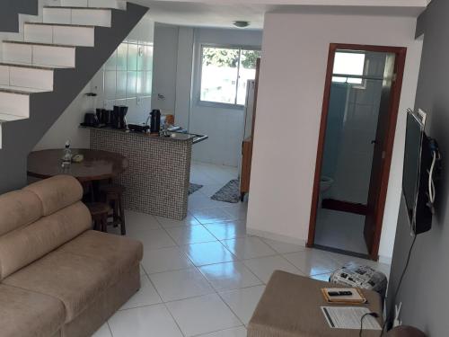 ein Wohnzimmer mit einem Sofa und einer Treppe in der Unterkunft Cobertura vista para o mar e piscina in Piúma
