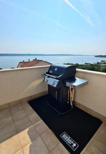 a grill on a balcony with a view of the ocean at OrkulaBliss Apartments in Pašman