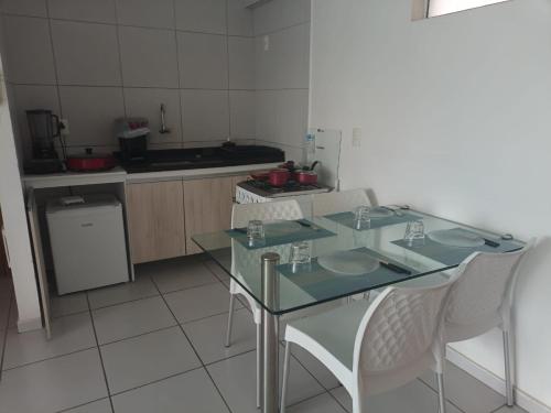 a kitchen with a glass table and white chairs at Apartamento West Flat in Mossoró