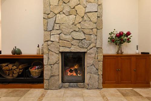 a fireplace in a living room with a stone wall at Twelve on Albert in Beechworth