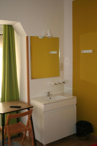 a bathroom with a sink and a mirror and a table at Hostal Juventus in Portbou