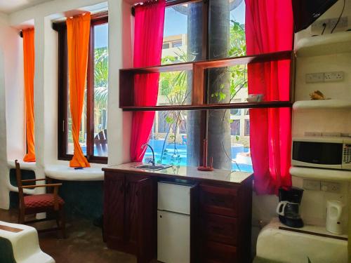 a kitchen with red curtains and a sink and a window at Reef View Pavilions - Villas & Condos in Lance aux Épines
