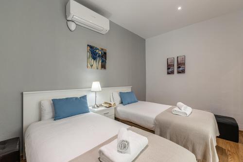 Pokój z 2 łóżkami i niebieskimi poduszkami w obiekcie Waou Apartamentos en Sol Confort 3 w Madrycie