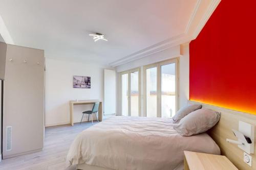 une chambre avec un lit et un mur rouge dans l'établissement 03.Studio#Creteil#Loft#Cinéma#Terrasse, à Créteil