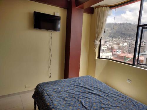um quarto com uma cama, uma televisão e uma janela em Ideal para descansar em Ambato