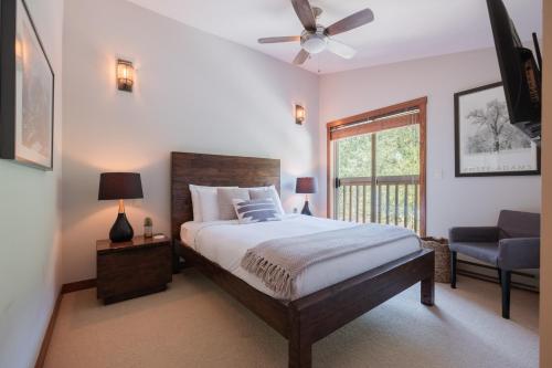 a bedroom with a bed with a ceiling fan and a chair at Taluswood Bluffs by Outpost Whistler in Whistler