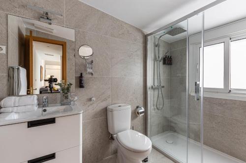 uma casa de banho com um WC e uma cabina de duche em vidro. em BNBHolder Apartamentos en Sol Confort 1 em Madri
