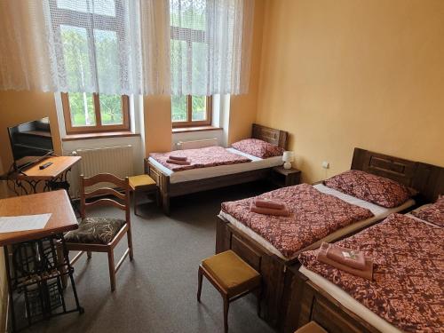 a room with three beds and a table and chairs at Hotel Max Šimek in Ostrava