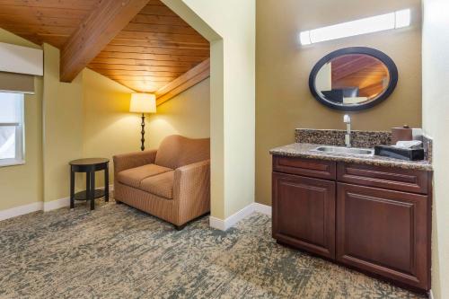 a bathroom with a sink and a chair and a mirror at Best Western Plus Wilmington/Carolina Beach in Wilmington