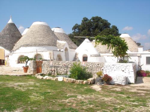 a house with thatched roofs and a stone wall at Masseria Ferri in Ostuni