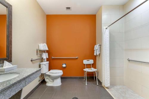 a bathroom with a toilet and an orange wall at Best Western Plus Longhorn Inn & Suites in Luling
