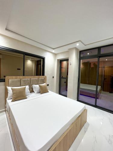 Royal Rif Al Hoceima في الحسيمة: سرير أبيض كبير في غرفة بها نوافذ