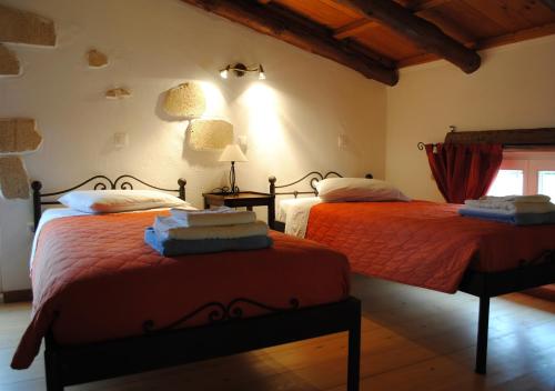 a bedroom with two beds with red sheets and a window at Rock House's Villa Melody in Plataniás
