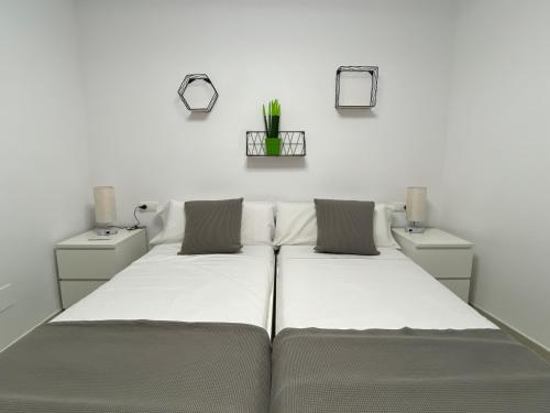 2 łóżka w pokoju z białymi ścianami w obiekcie APARTAMENTS L’ARC w mieście Palafrugell