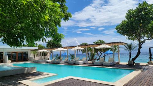 a swimming pool with chairs and umbrellas next to the ocean at AMP Beach House in Nusa Penida