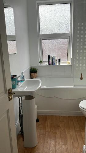 łazienka z umywalką, wanną i oknem w obiekcie Home Away From Home 家外之家 D w mieście Belfast