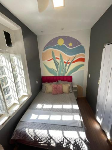 a bedroom with a bed with a painting on the wall at Aurora Hostel Rio in Rio de Janeiro