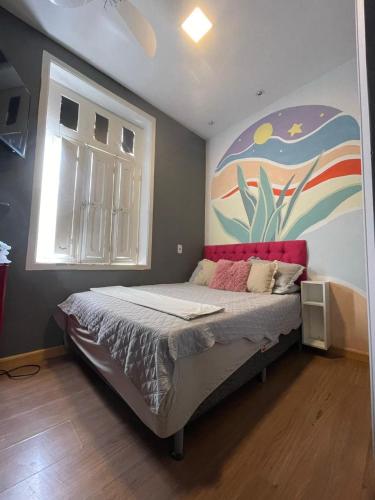 a bedroom with a bed with a painting on the wall at Aurora Hostel Rio in Rio de Janeiro