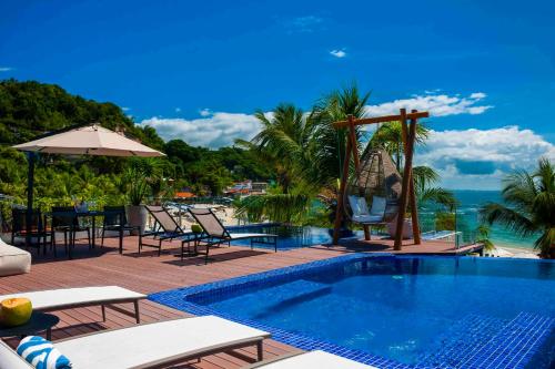 a swimming pool with chairs and tables and the ocean at Pousada Bahia Tambor in Morro de São Paulo