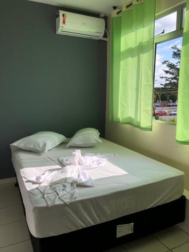 a bedroom with a bed with white sheets and a window at Hotel Rodeio in Lages