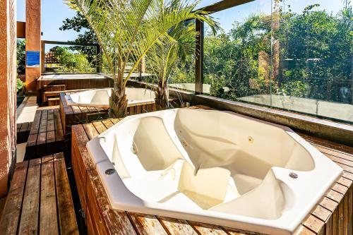 eine Badewanne auf einer Holzterrasse mit Fenstern in der Unterkunft Resort pé na areia - Studios direto com proprietário JBVJR in Florianópolis